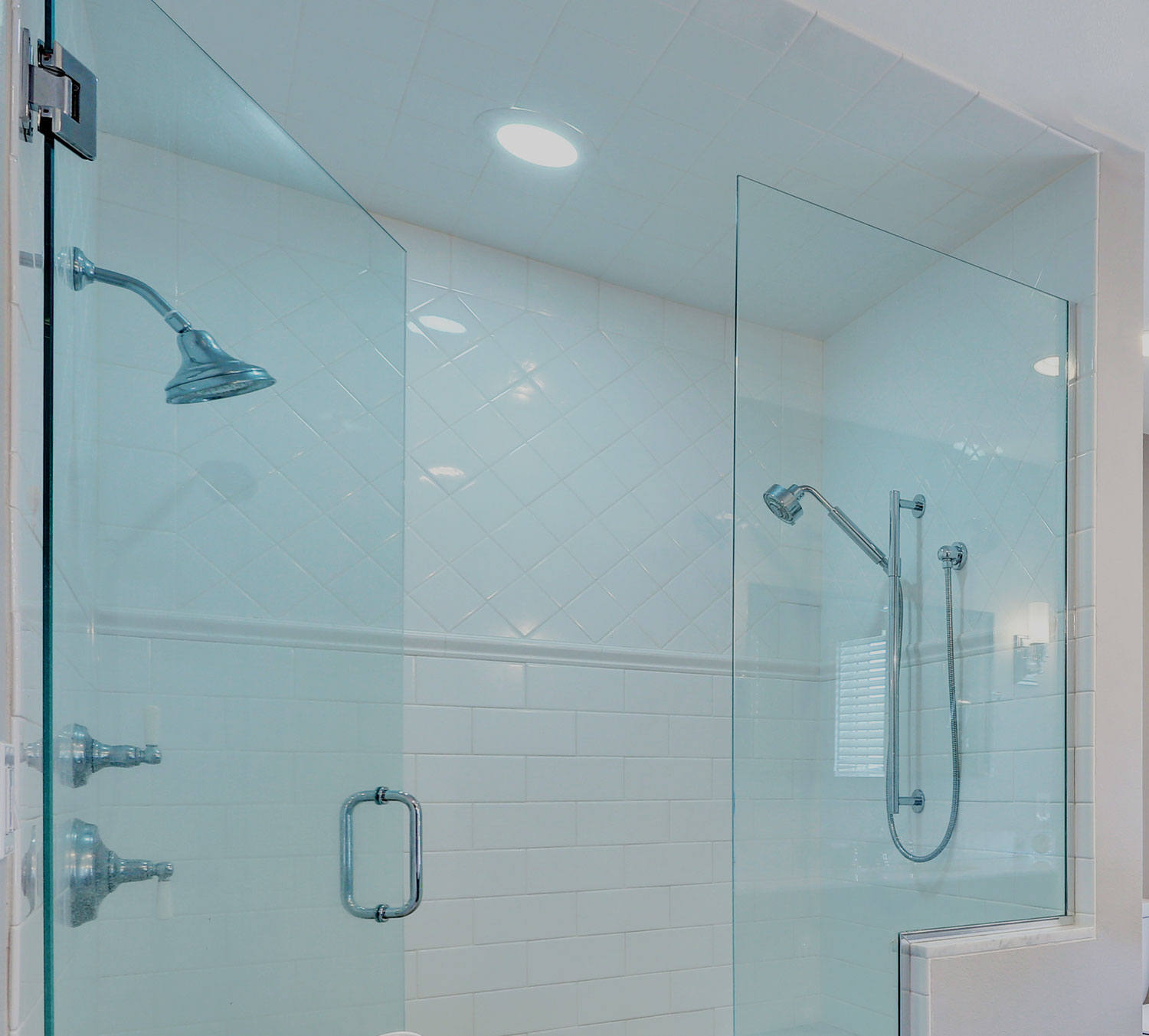 Walk in shower enclosed with frameless glass panels and white subway tiling